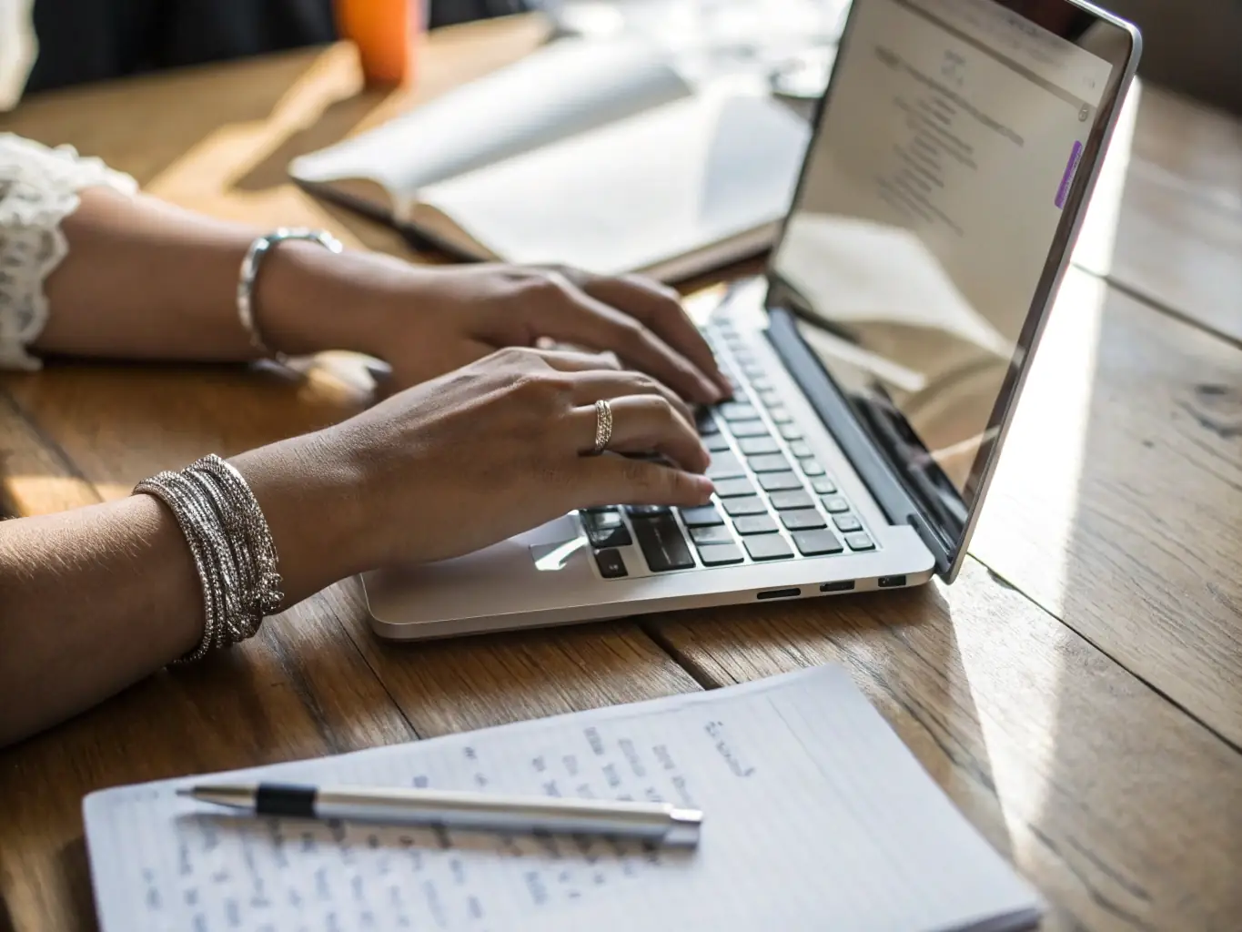 A close-up shot of a student's hands typing on a laptop, with a resume template visible on the screen, symbolizing the process of crafting a professional resume.